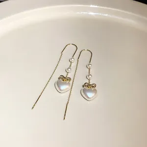 Detaillierte Nahaufnahme eleganter Perlenherz-Ohrhänger mit goldenem Schleifen-Design