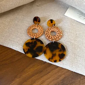 Detailed macro view of retro bohemian earrings with woven rattan and tortoise acrylic