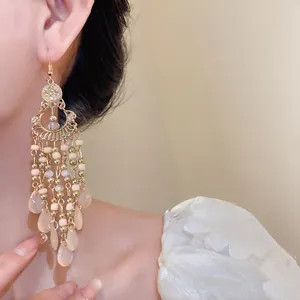 Primo piano di orecchini pendenti boho con perline rosa e ciondoli a goccia d'acqua