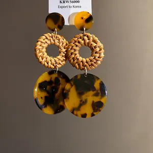 Detail of ethnic straw woven earrings with amber-colored tortoiseshell pattern discs