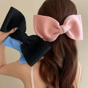 Close-up of oversized pink, black, and blue bow hair clips on long brown hair