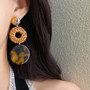 Close-up of bohemian woven rattan and tortoise shell resin drop earrings for women.