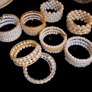 Detailed view of layered pearl and rhinestone wrap bracelets in gold and silver finish.