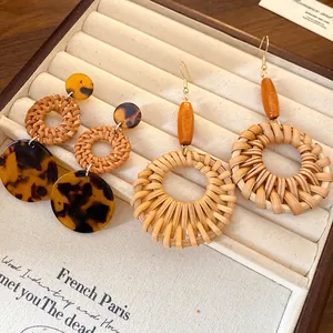 Detailed shot of bohemian rattan woven earrings with wooden beads in a tray