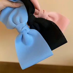 Detailed view of large fabric bow hair clips showing blue black and pink color options