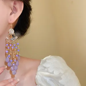 Primo piano di orecchini boho con perline di vetro viola e pendenti a goccia d'acqua