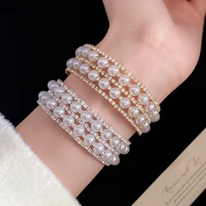 Close-up detail of elegant multi-layer pearl bracelets with rhinestones on a wrist.