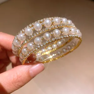 Close-up of elegant multi-layer bracelet with white pearls and sparkling rhinestones.
