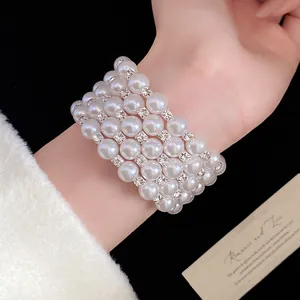 Close-up of a multi-layer pearl bracelet with rhinestone spacers on a wrist.