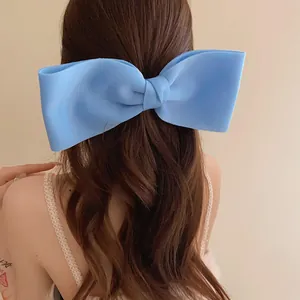 Close-up of a large light blue bow hair clip worn on wavy brown hair