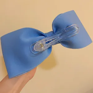 Close-up view of blue fabric bow hair clip featuring a clear plastic duckbill mechanism