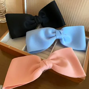 Close-up of three elegant fabric bow hair clips in black, blue, and pink colors