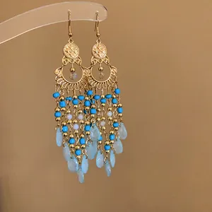 Primo piano di orecchini bohemian con perle di vetro blu e ciondoli a goccia azzurri