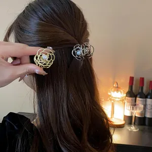 Vista dettagliata di un'elegante pinza per capelli in metallo a fiore con perla centrale