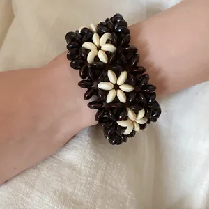 Macro detail of a bohemian style wood bead bracelet featuring a flower pattern