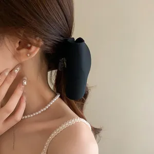Side view of model wearing a minimalist black bow hair claw clip in lifestyle setting.