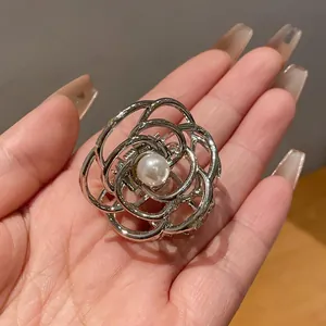 Dettaglio ravvicinato di una molletta per capelli a forma di rosa in metallo con perla bianca