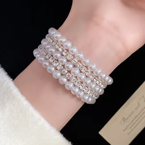 Detailed view of an elegant multi-layer pearl and rhinestone bracelet on a wrist