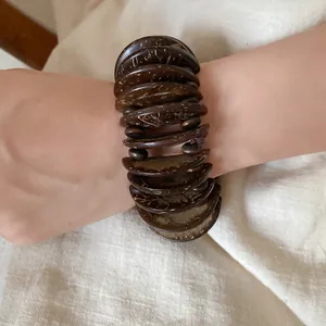 Close-up of a Bohemian ethnic style stacked coconut shell disc bracelet on wrist