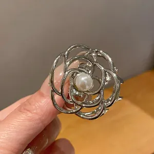 Primo piano di una molletta per capelli a forma di rosa in metallo argento con perla