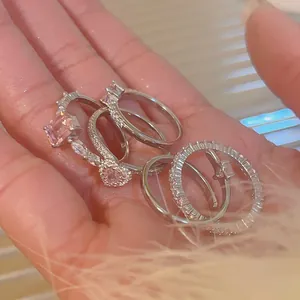 Detailed macro view of multiple silver zircon rings featuring heart and geometric shapes
