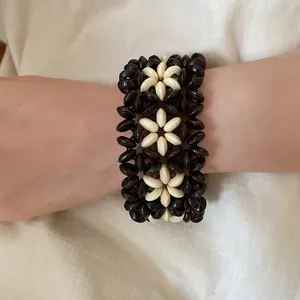 Detailed macro view of bohemian handmade wooden beaded flower bracelet worn on wrist