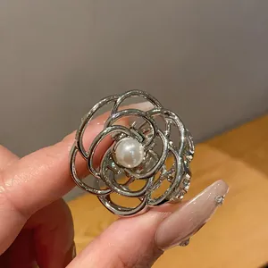 Dettaglio di una molletta per capelli in metallo argento con elegante fiore di perla.