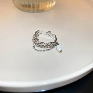 Close-up of a silver molten texture open ring featuring a dangling pearl and ball chain detail