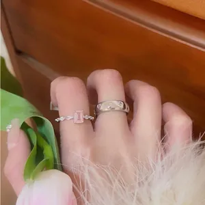 Close-up of pink heart and rectangular zircon rings on hand with floral prop context