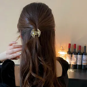 Elegante molletta a fiore in metallo dorato con perla mostrata su lunghi capelli castani