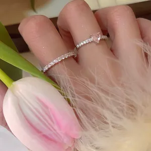 Close-up of heart-shaped pink zircon ring with elegant tulip and feather background