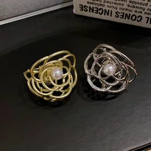 Dettaglio di eleganti mollette in metallo a forma di rosa con perle in oro e argento