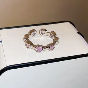Close-up of a silver-toned open ring set with sparkling pink heart-shaped zircons.