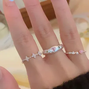 Close-up of three dainty Korean style rings with zircon hearts and flowers