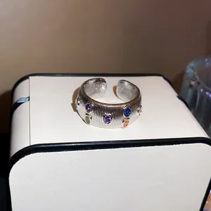 Detailed view of a silver textured open ring with vibrant multi-color zircon gemstones