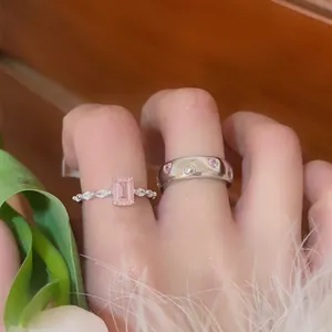 Close-up of elegant pink zircon heart rings and emerald cut stone ring on fingers.