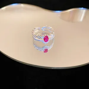 Macro view of a silver geometric open ring featuring a vibrant red oval zircon gemstone