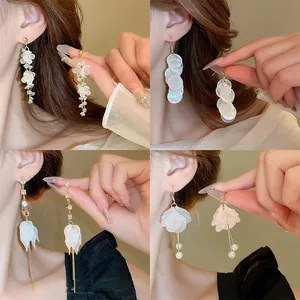Detail view of four unique Korean style floral and pearl tassel earrings shown on ear