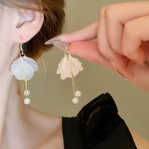Detailed view of elegant flower petal earrings with pearl tassels on a model's ear