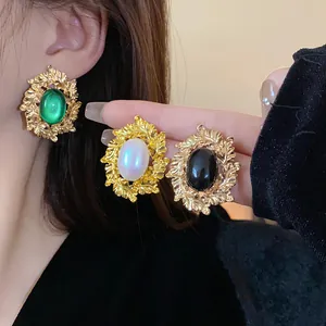 Close-up of vintage gold leaf oval earrings with green, white, and black stones