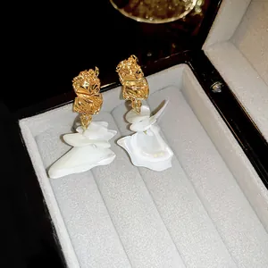 Close-up of elegant gold and white petal-shaped dangling earrings in a jewelry box
