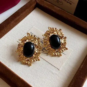 Close-up macro view of vintage gold leaf earrings with a large black oval stone center