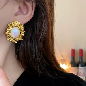 Close-up of vintage gold leaf stud earrings with an elegant white oval pearl centerpiece