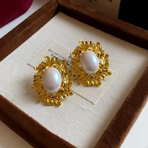 Close-up of vintage oval leaf earrings with pearl center and golden metal texture