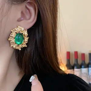 Detail shot of vintage golden wreath earrings featuring a vivid green oval gemstone inlay