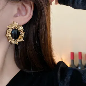 Detailed macro view of vintage gold-tone leaf earrings featuring a black oval cabochon stone