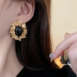 Detailed view of vintage gold leaf stud earrings featuring a polished black oval stone center