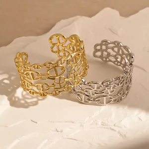 Primo piano di bracciali rigidi multistrato a maglia ancora in oro e argento su pietra.