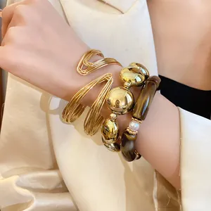 Close-up of stacked gold wire bangle and marbled acrylic pearl stretch bracelets