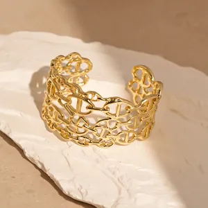 Dettaglio di un bracciale rigido aperto dorato a più strati con maglie a naso di maiale